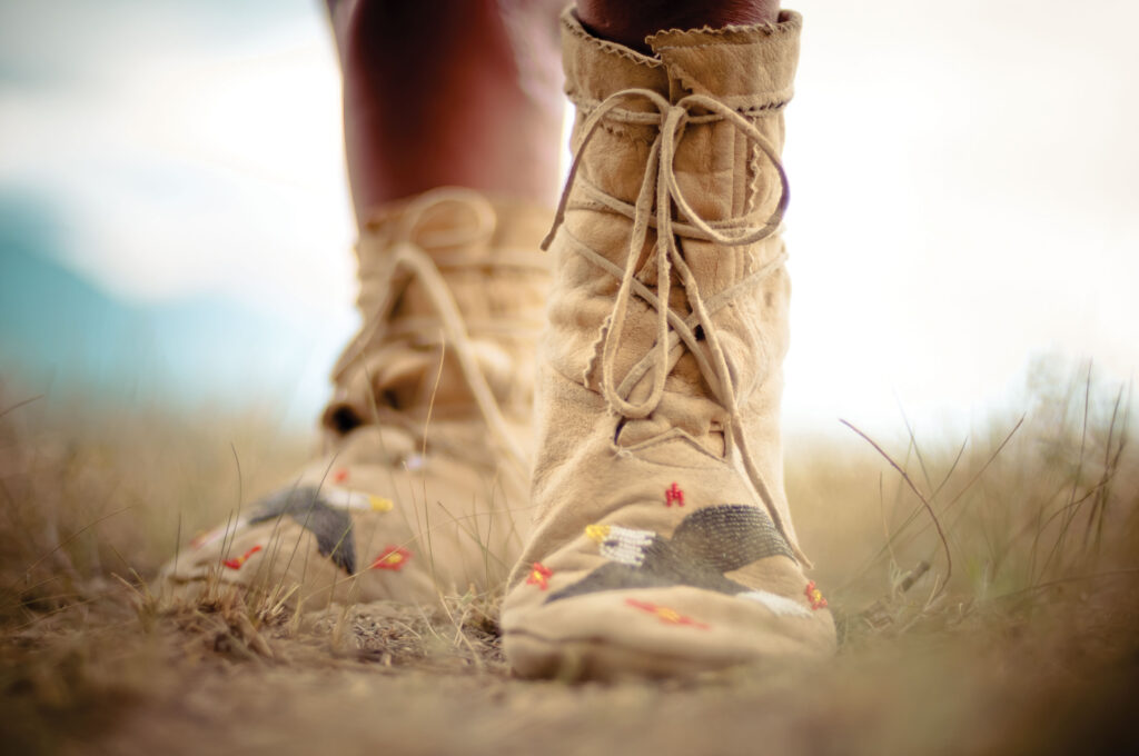 A front facing view of traditional moccasins with beadwork of an eagle on each foot.