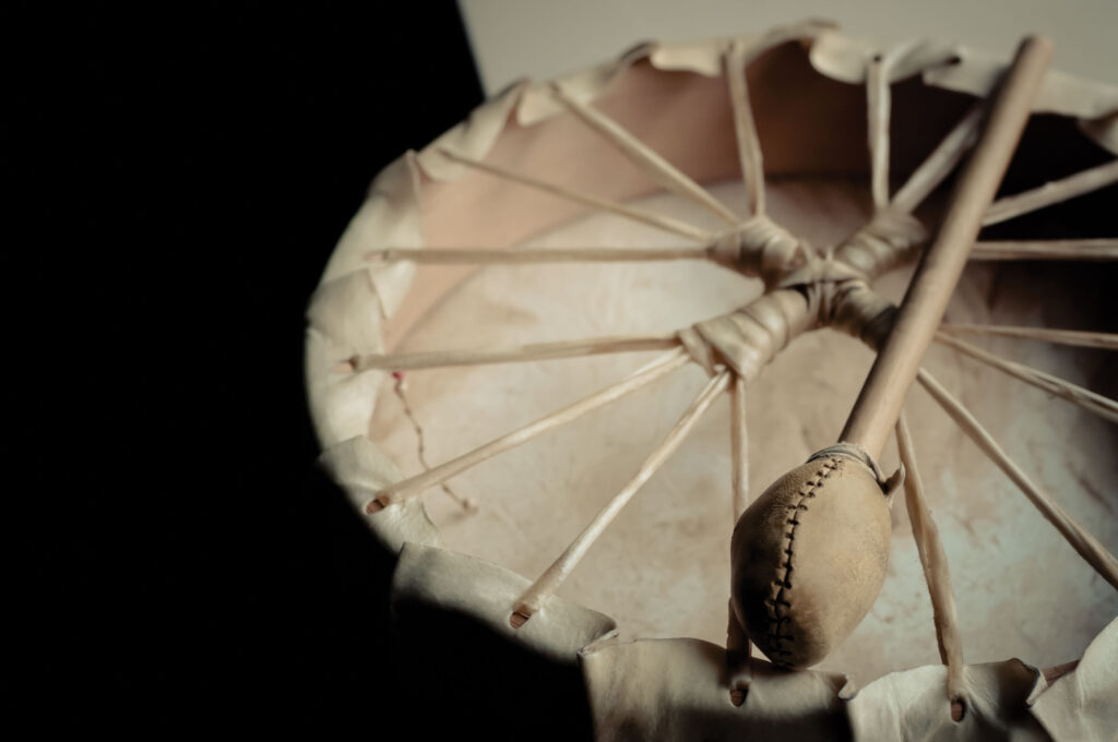 A closeup of a hand-made drum with a stick resting on it